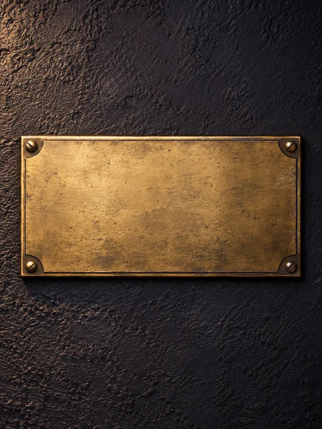 A blank brass number plaque on a dark wall